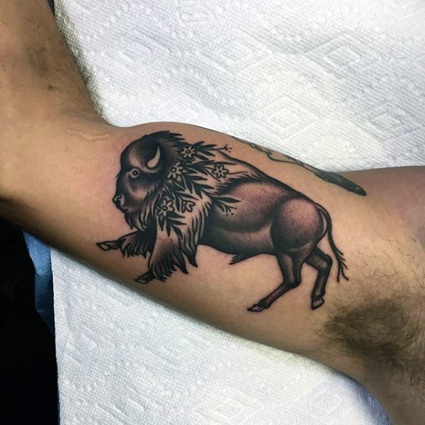 Colored small biceps tattoo of running bull with flowers