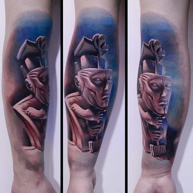 Colored surrealism style colored arm tattoo of creepy statue