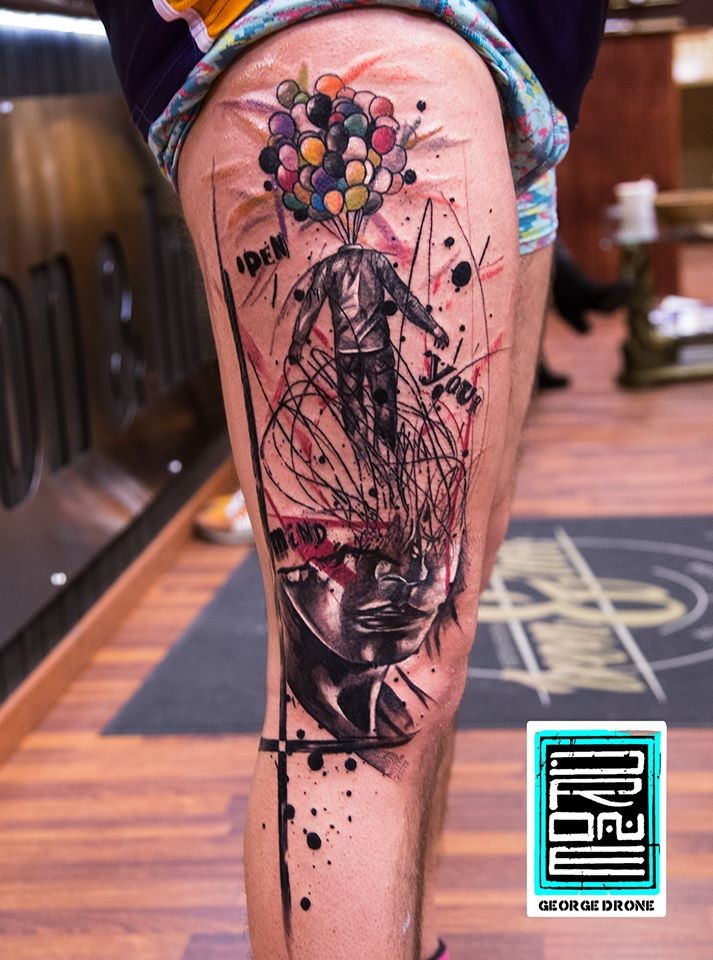 Colored surrealism style colored thigh tattoo of man with balloon head with lettering