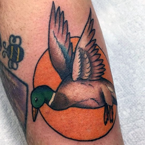 Colored typical old school style tattoo of flying duck and orange circle