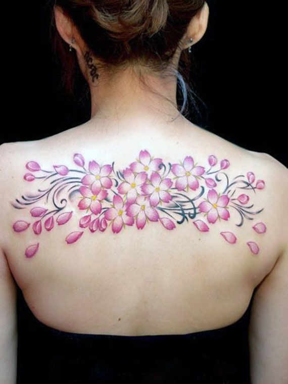 Colored upper back tattoo of pink flowers