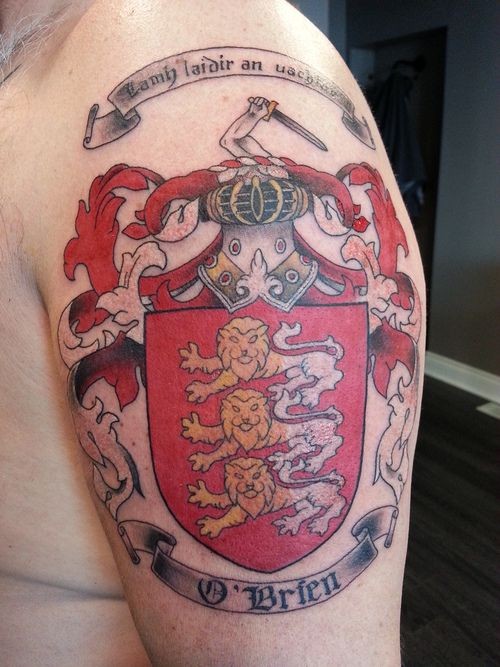 Colorful family crest with motto and lions tattoo on shoulder