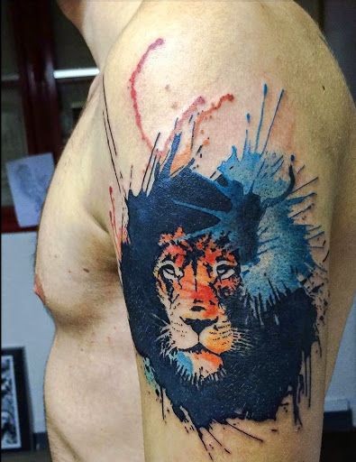 Tatuaggio con testa di leone colorato sulla spalla in stile acquerello