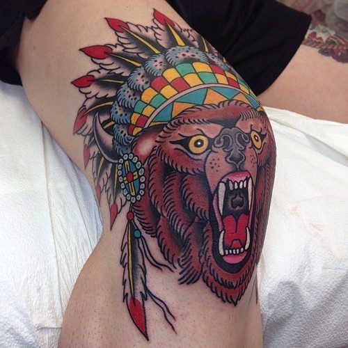 Colorful old school style knee tattoo of roaring bear with Indian helmet