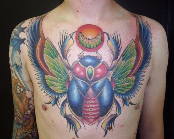 Tatuaje en el pecho,  escarabajo grande multicolor con larva