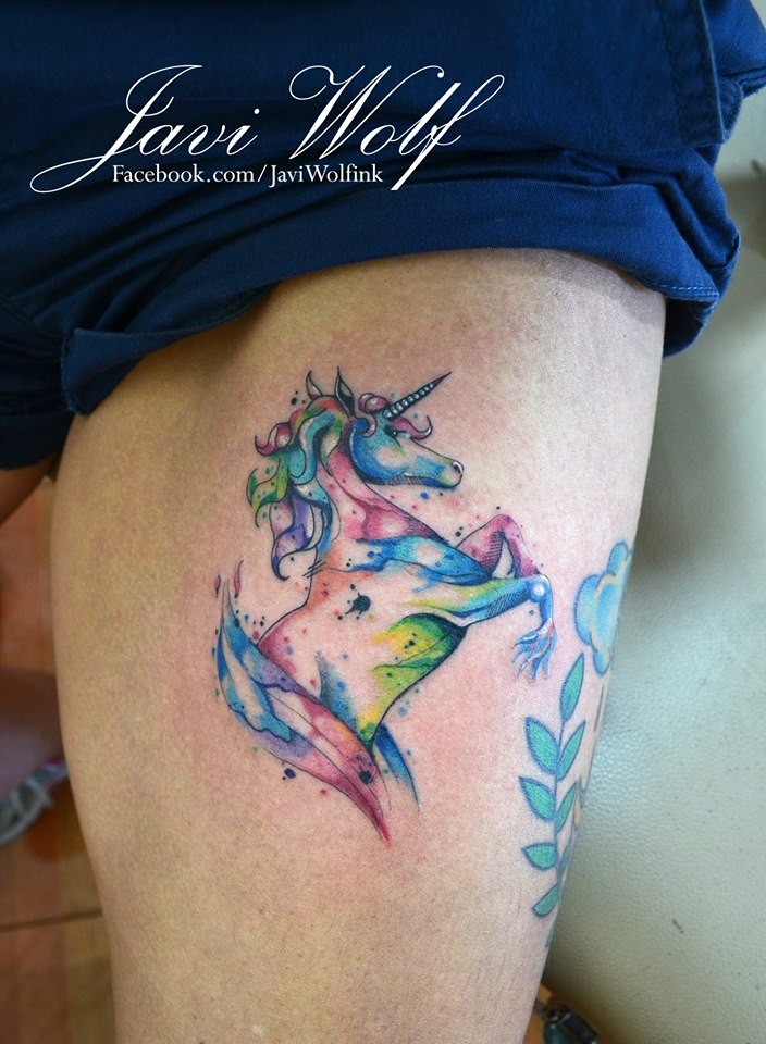 Buntes Einhorn Tattoo am Oberschenkel von Javi Wolf mit Farbentropfen im Aquarell Stil