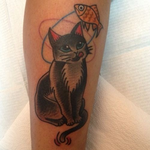 Coloured cat thinking of fish tattoo on leg