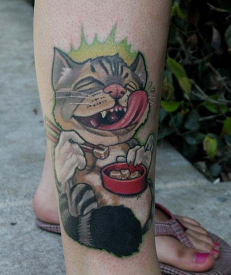 Tatuaje coloreado en la pierna de un gato comiendo.