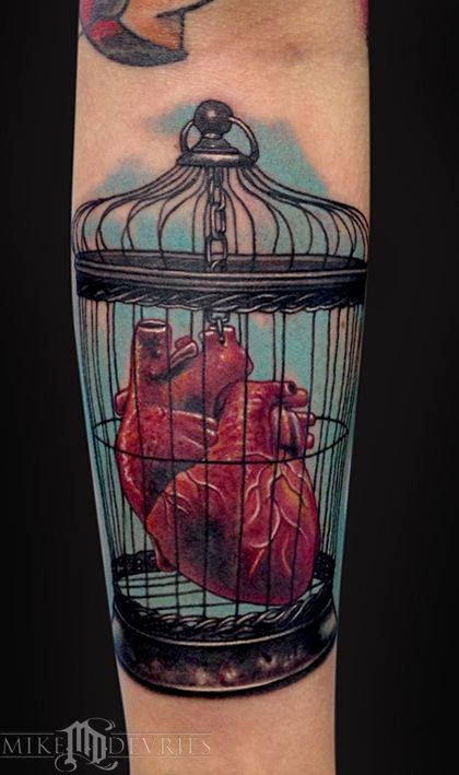Coloured heart in a bird cage tattoo