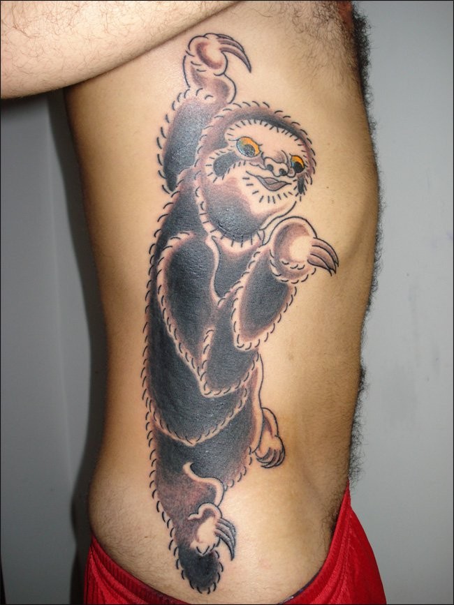 Coloured sloth with orange eyes tattoo on ribs