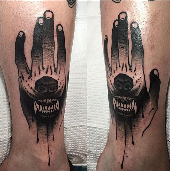 Libro de cómics tatuaje de pierna con tinta negra pintado por Michael J Kelly de mano estilizada con dientes de perro