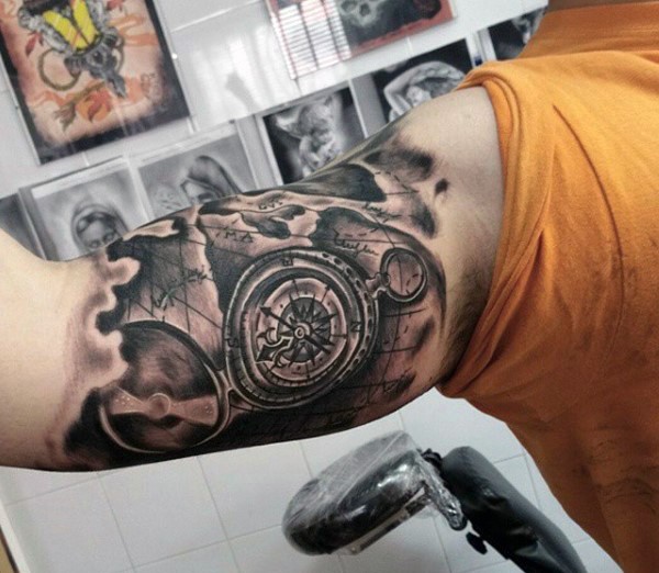 Compass and map elements realistic tattoo in torn skin on biceps