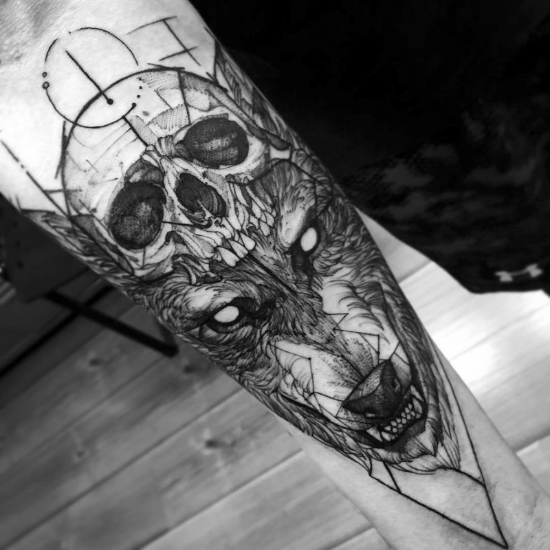 Cool black ink detailed demonic beast face tattoo on forearm stylized with human skull
