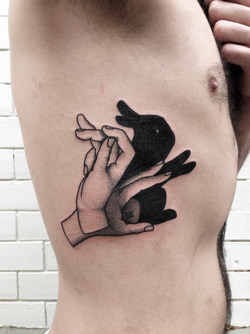 Tatuaje en las costillas, sombra de conejo con las manos