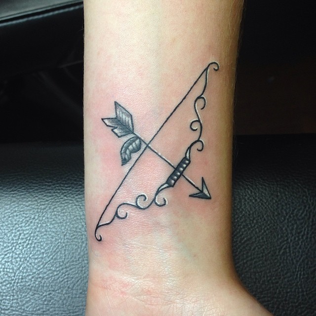 Tatuaje en la muñeca,
 arco y flecha metálicos