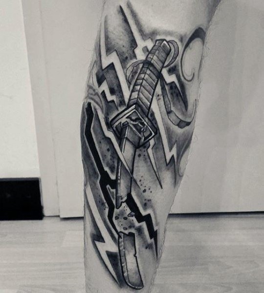 Tatuaje de espada rota  en la pierna, colores negro blanco