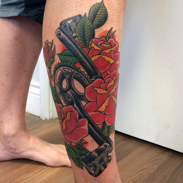 Cool cycling themed colored tattoo with pedals and flowers on leg