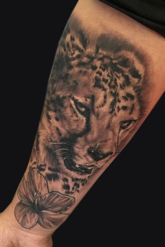 Tatuaje en el antebrazo,
guepardo y flor, diseño de color gris y negro