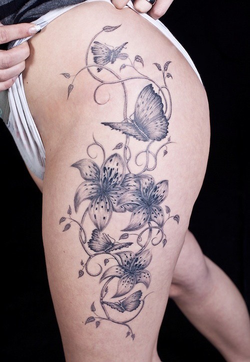 Coole graue Blumen auf gewelltem Ast und Vogel Tattoo am Oberschenkel