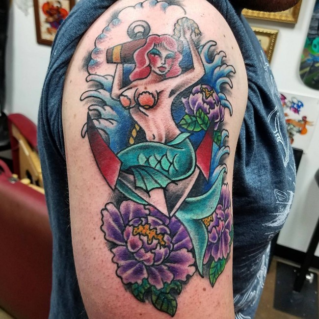 Cool looking colored mermaid tattoo on shoulder with various flowers and anchor