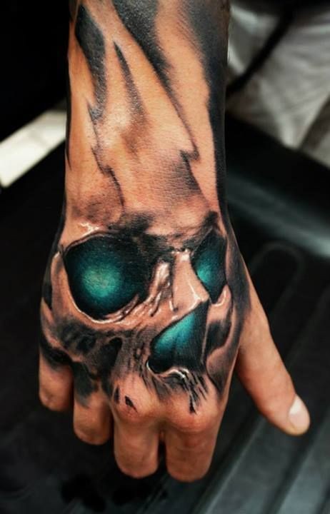 Tatuaje en la mano,  cráneo con ojos de color esmeralda