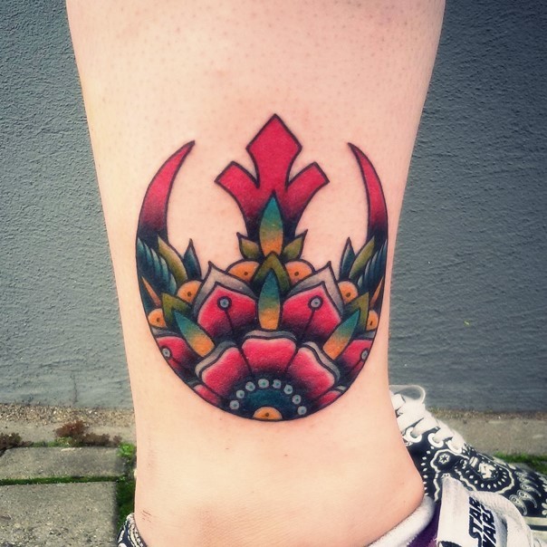 Cool red colored Rebel Alliance emblem tattoo on ankle stylized with multicolored flower
