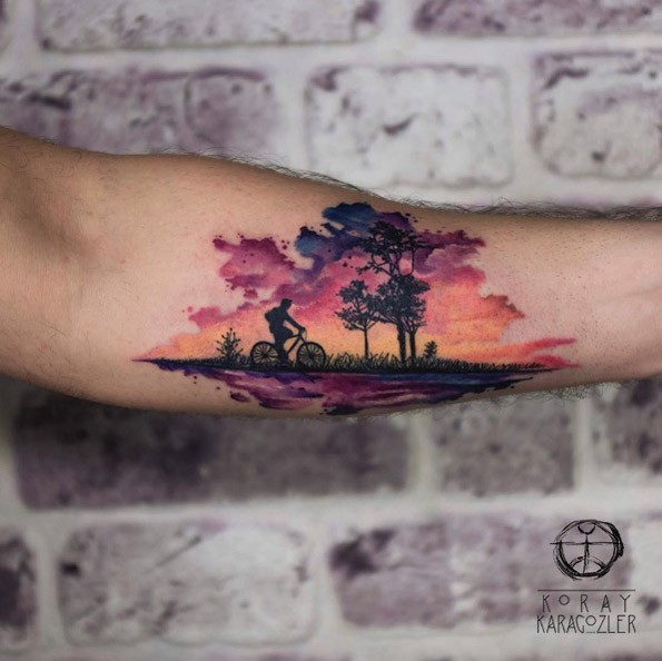 Criativo agradável pintado tatuagem antebraço colorido do homem andando de bicicleta