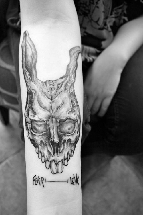 Creepy cult like black ink bunny skull with lettering on arm