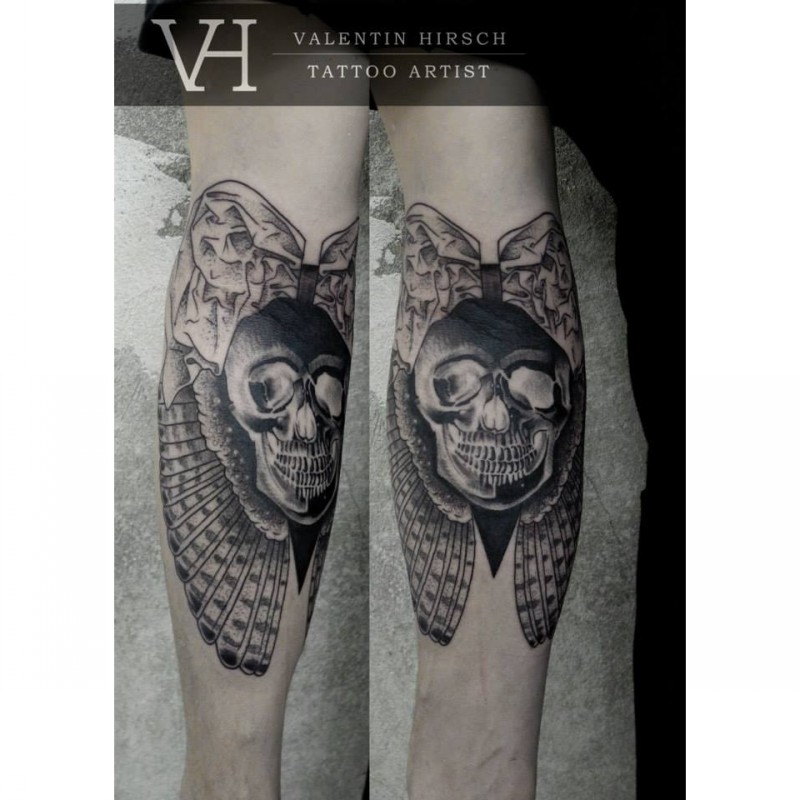 Creepy designed and colored human skull with wings tattoo on forearm