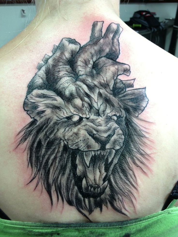 Creepy horror style upper back tattoo of roaring lion with human heart