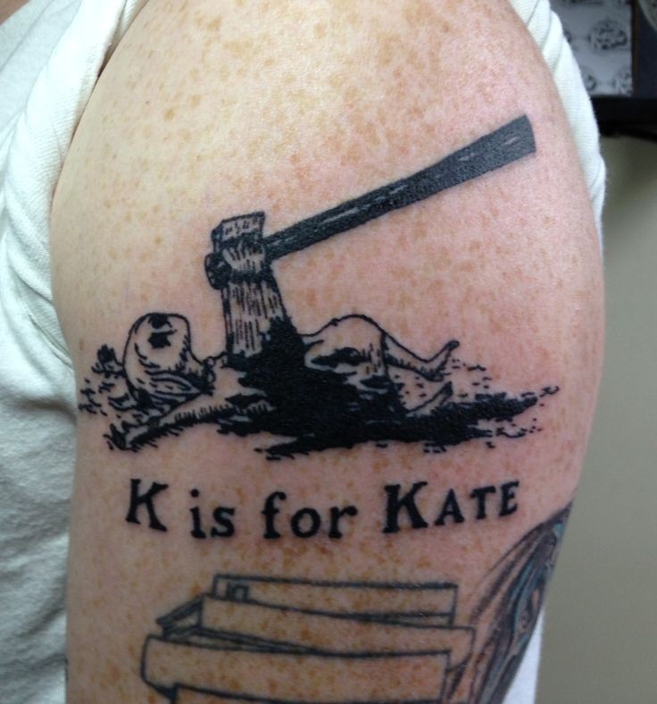 Creepy looking black ink shoulder tattoo of woman with axe and lettering