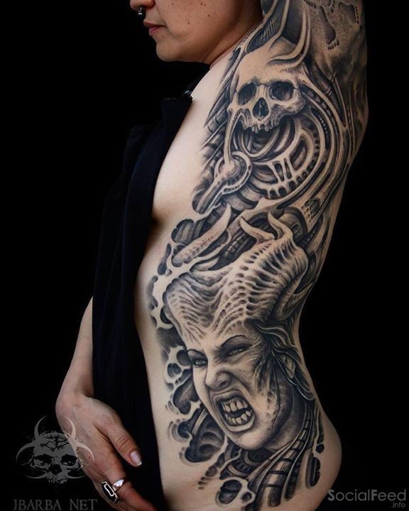 Creepy looking black ink side and arm tattoo of demonic woman with skull