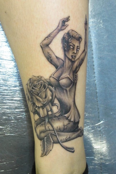 Creepy painted black and white seductive zombie woman tattoo with flower on thigh