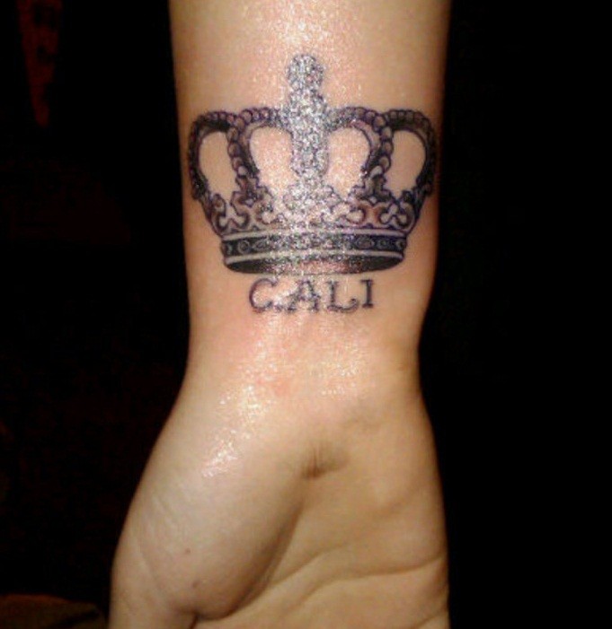 Tatuaje en la muñeca, corona de reina y nombre cali