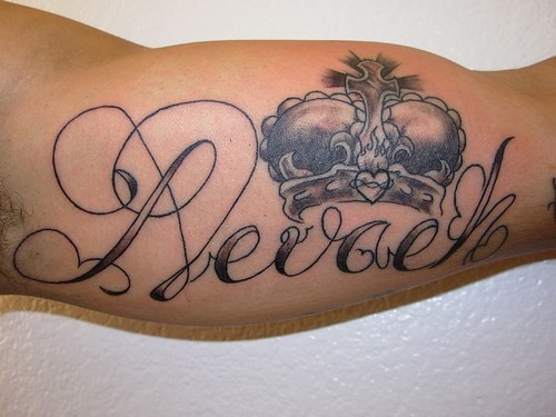 Crown tattoo with script on biceps