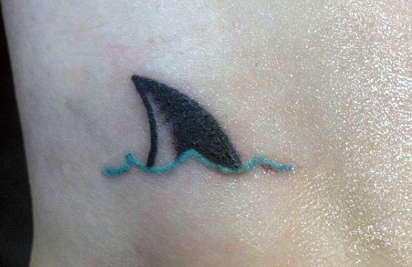 Cute and tine colored shark fin tattoo on ankle