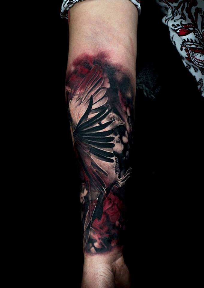Cute black and red bird tattoo on forearm