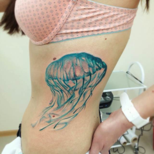 Tatuaje en las costillas,
medusa ancha de color azul claro