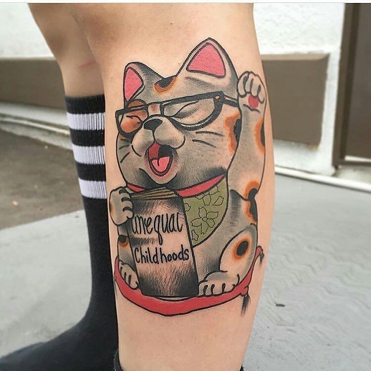 Cute cartoon style colored leg tattoo of maneki neko japanese lucky cat with book and glasses
