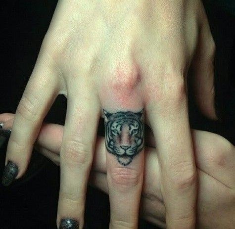 Cute little cartoon like tiger tattoo on finger