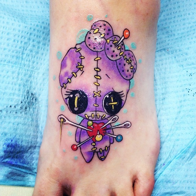 Cute little colored watercolor style painted foot tattoo of baby voodoo doll