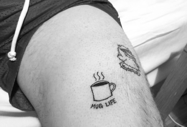 Nettes kleines hausgemachtes schwarzes Tattoomit  Kaffeetasse und Schriftzug Tattoo am Oberschenkel
