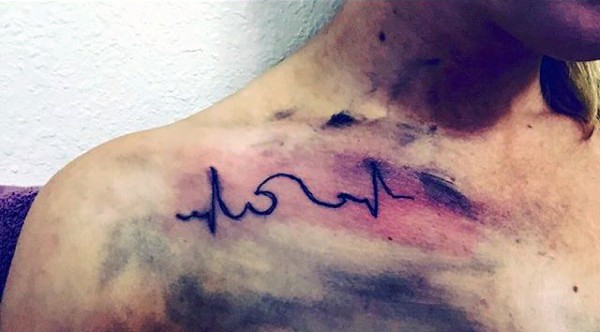 Dark black ink heart rhythm shoulder tattoo with wave