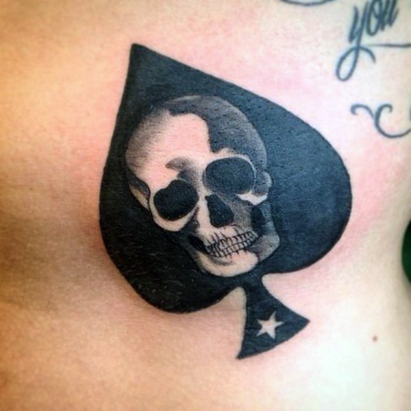 Dunkles schwarzes Pik-Symbol mit dem Schädel und winzigem Stern Tattoo