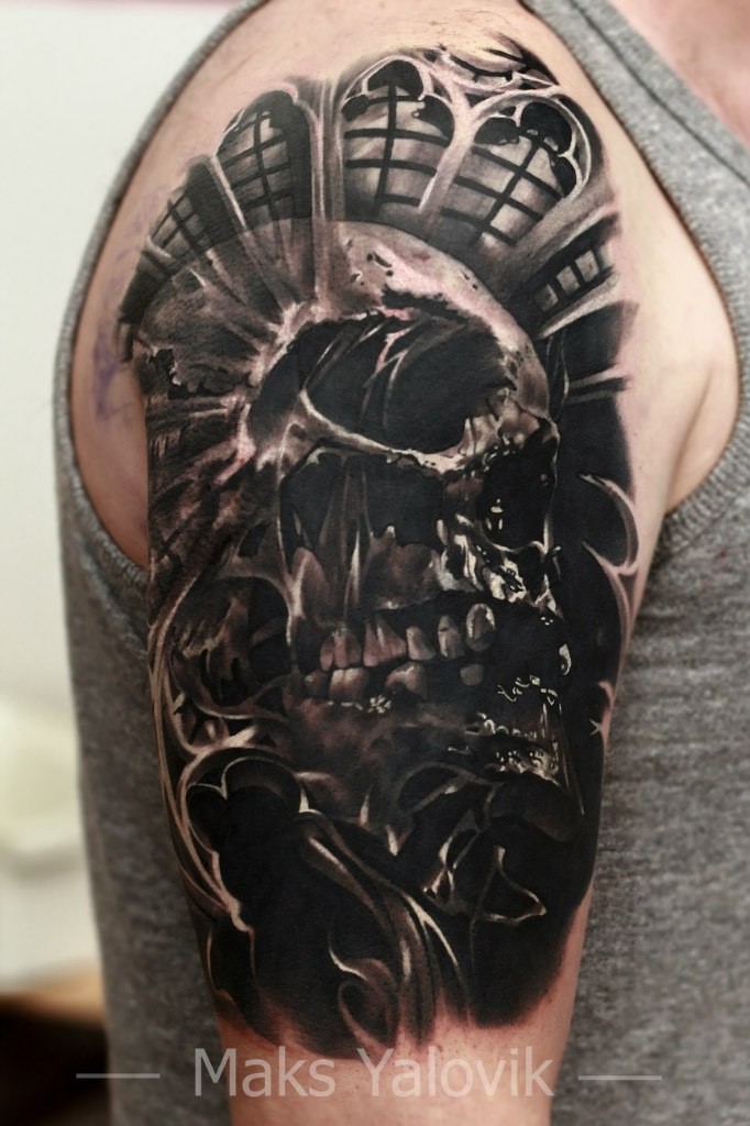 Dark realistic looking shoulder tattoo of human skull with ornaments