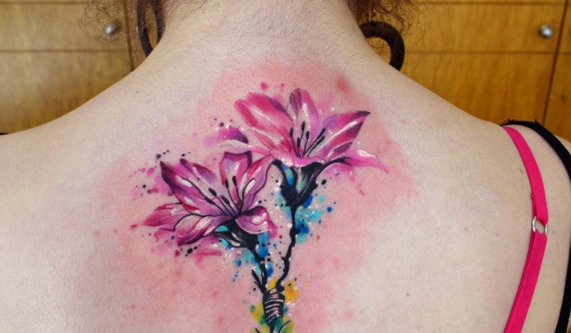 Delicate pink lily flowers tattoo on upper back in watercolor style