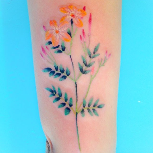 Tatuaje en el antebrazo,
flor silvestre delicada de varios colores