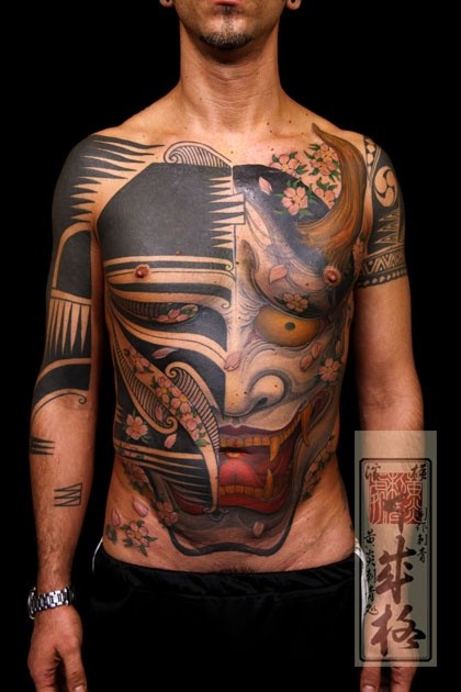 Tatuaggio impressionante sul petto e sul stomacho la faccia del diavolo divisa in due visi