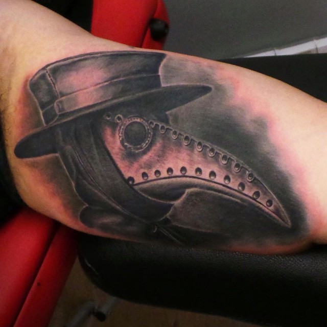 Detailed big biceps tattoo of plague doctor with old hat