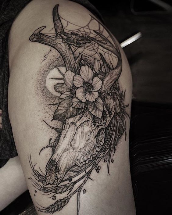 Dot style black ink thigh tattoo of large animal skull with flowers